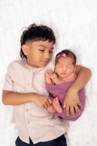 Sleeping newborn baby girl in a pink knitted romper holding a tiny teddy bear, illustrating the successful results of booking a newborn session within the first two weeks with Tender Beginnings Photo.