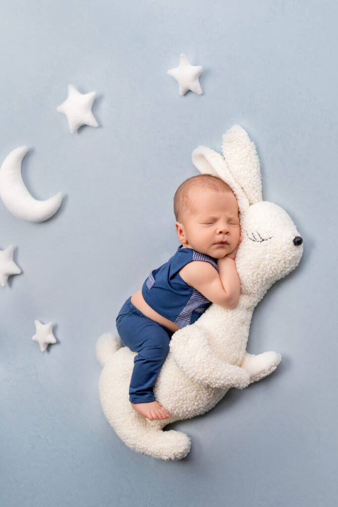 Dreamy newborn baby boy sleeping on a plush bunny prop, showcasing the sleepy professional poses achieved when booking your session during the second trimester with Tender Beginnings Photo.