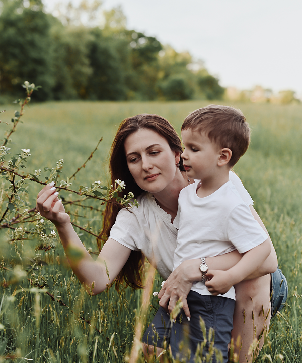 Yana Chuhaieva, founder of Tender Beginnings Photography, with her son in a spring field