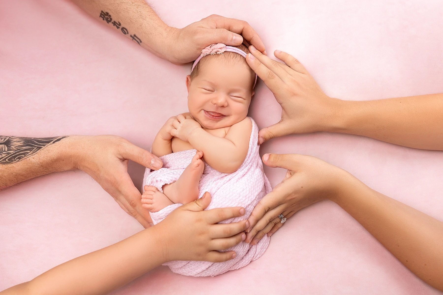 Parents' hands cradling their newborn's face during a photoshoot, shot by Tender Beginning