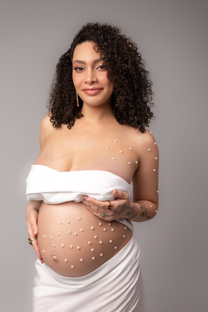 Pregnant woman in a white wrap, studio maternity photoshoot, shot by Tender Beginning