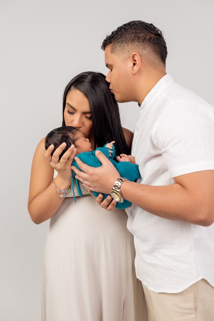 Parents holding their newborn baby, studio portrait, shot by Tender Beginning