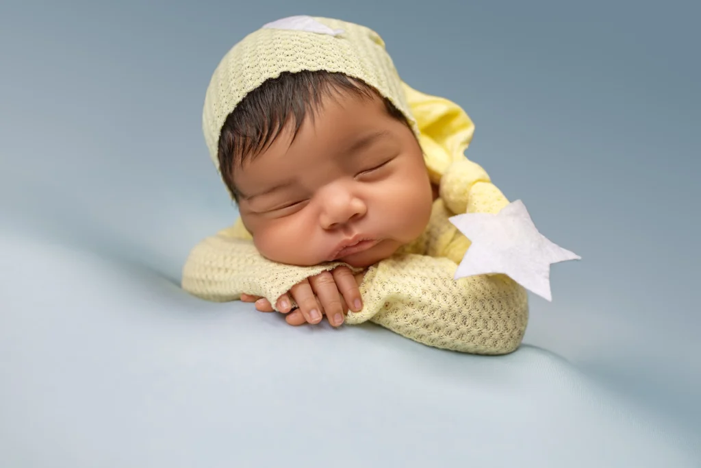 Sleeping baby in a bright yellow outfit resting on a blue background with a star prop, customized to the parents' color choices.