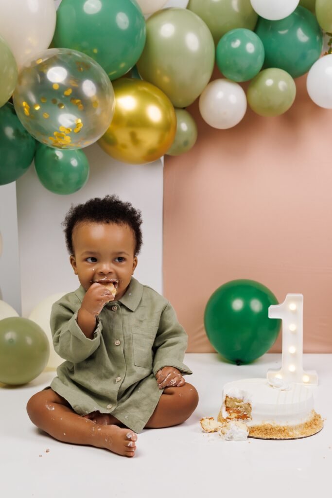 Toddler boy cake smash session with green and gold balloons, shot by Tender Beginning