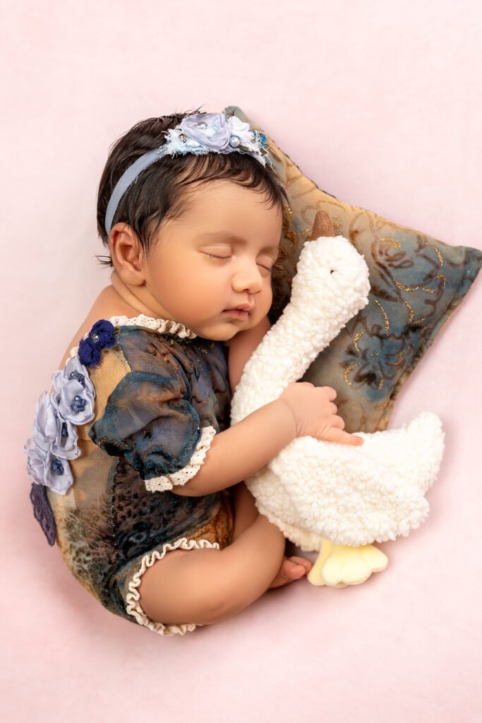 Newborn baby holding a stuffed toy, floral outfit, shot by Tender Beginning